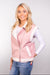 A close-up, front-facing view of our model, Lexi, wearing a light pink faux-leather vest with white sherpa trim.