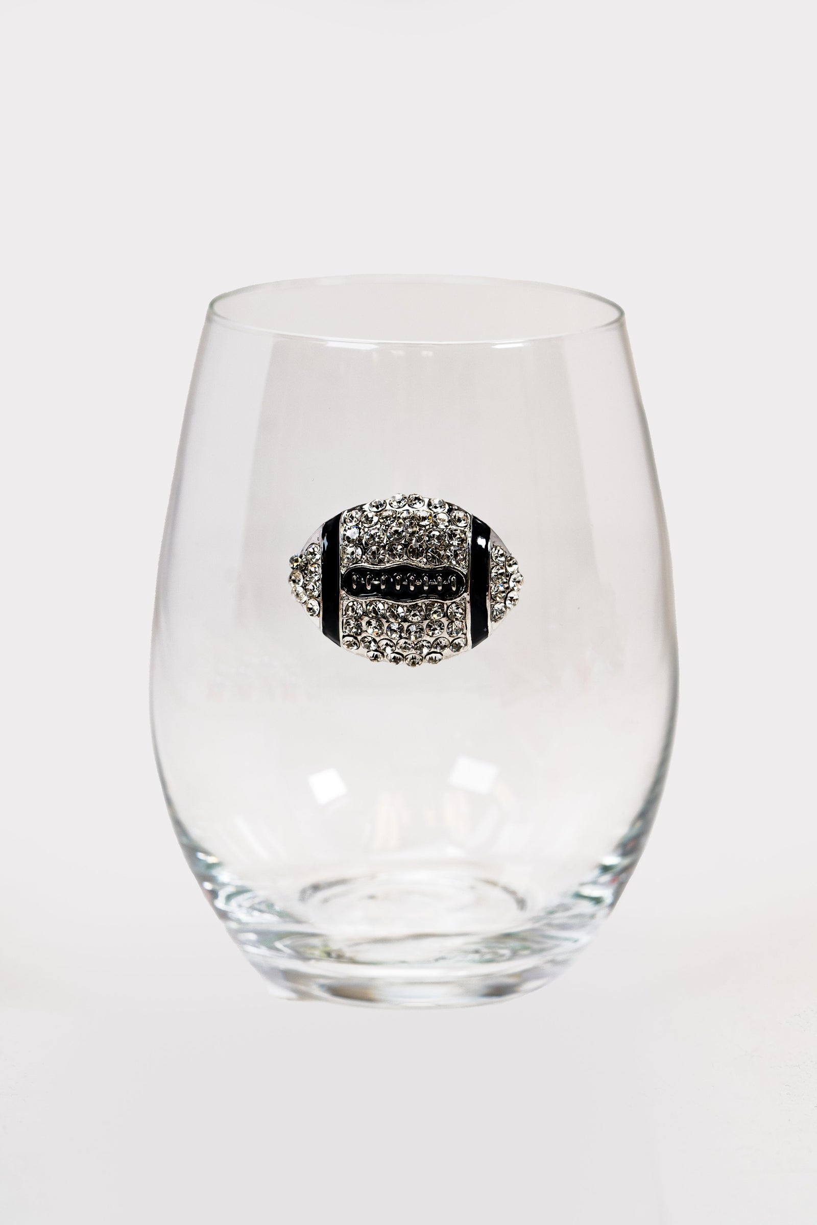 A stemless wine glass with a silver and black rhinestone football on the front.