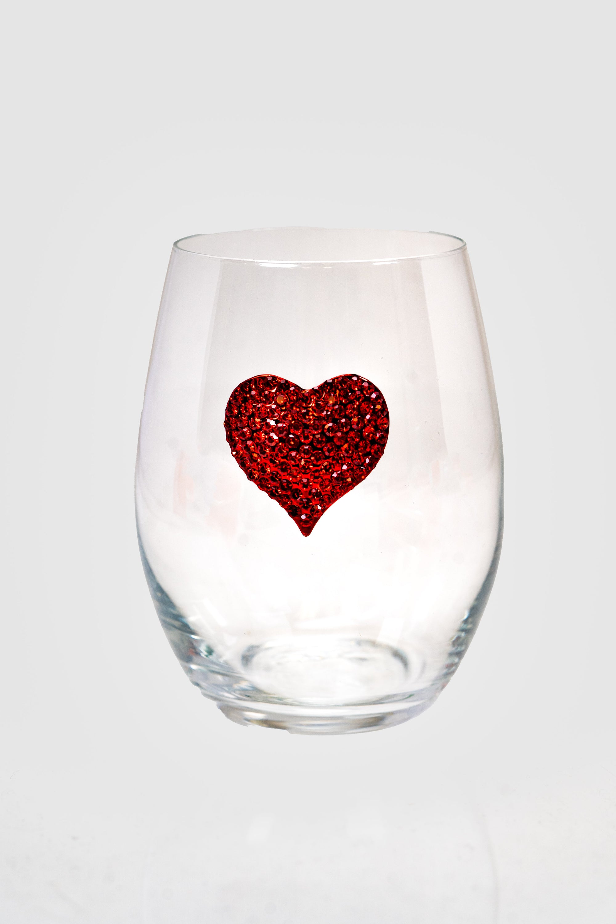 A stemless wine glass with a red rhinestone heart on the front.