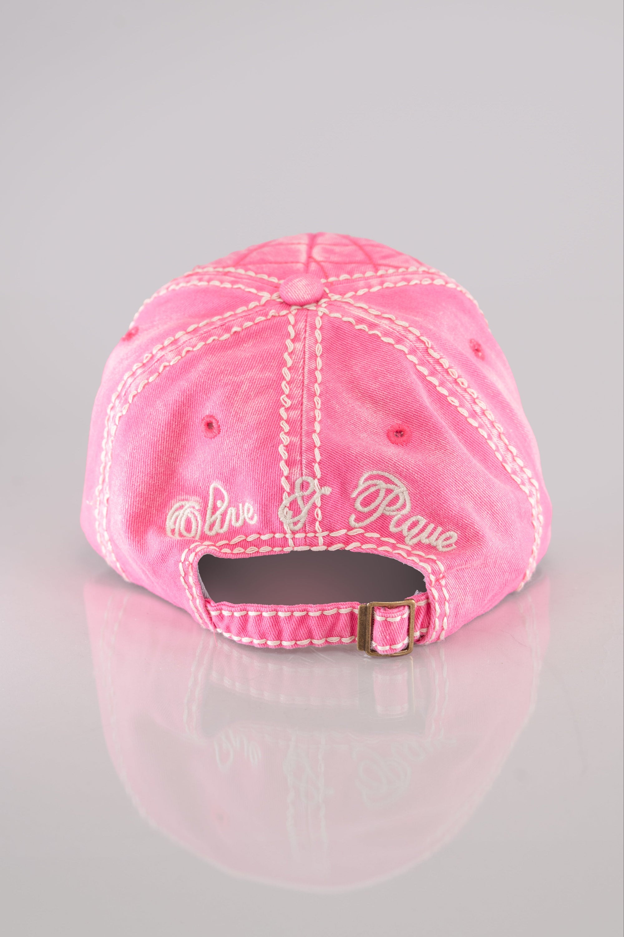 A back view of a bright pink quilted baseball cap with a large rhinestone flower embellished on the front and white stitching detail throughout.