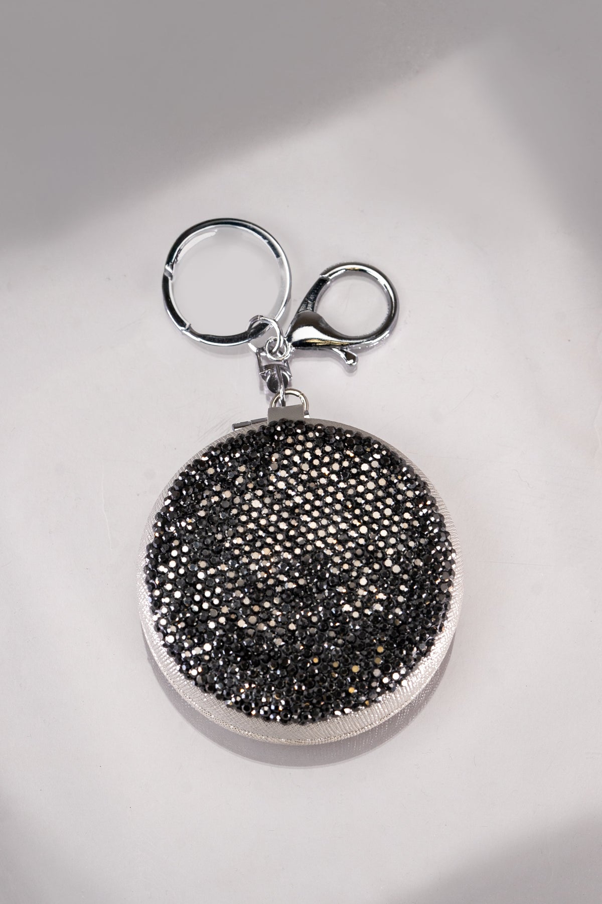 A round black and silver rhinestone double mirror compact keychain.