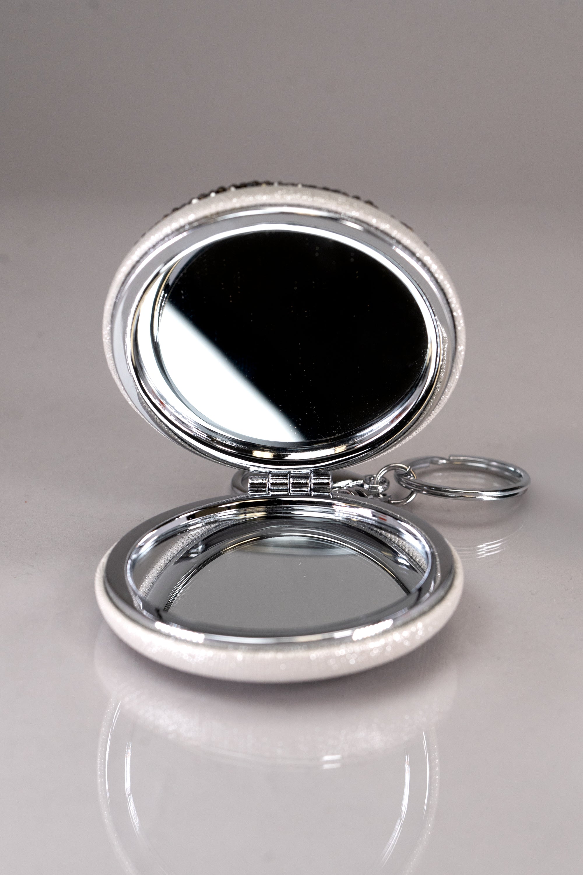 A round black and silver rhinestone double mirror compact keychain.