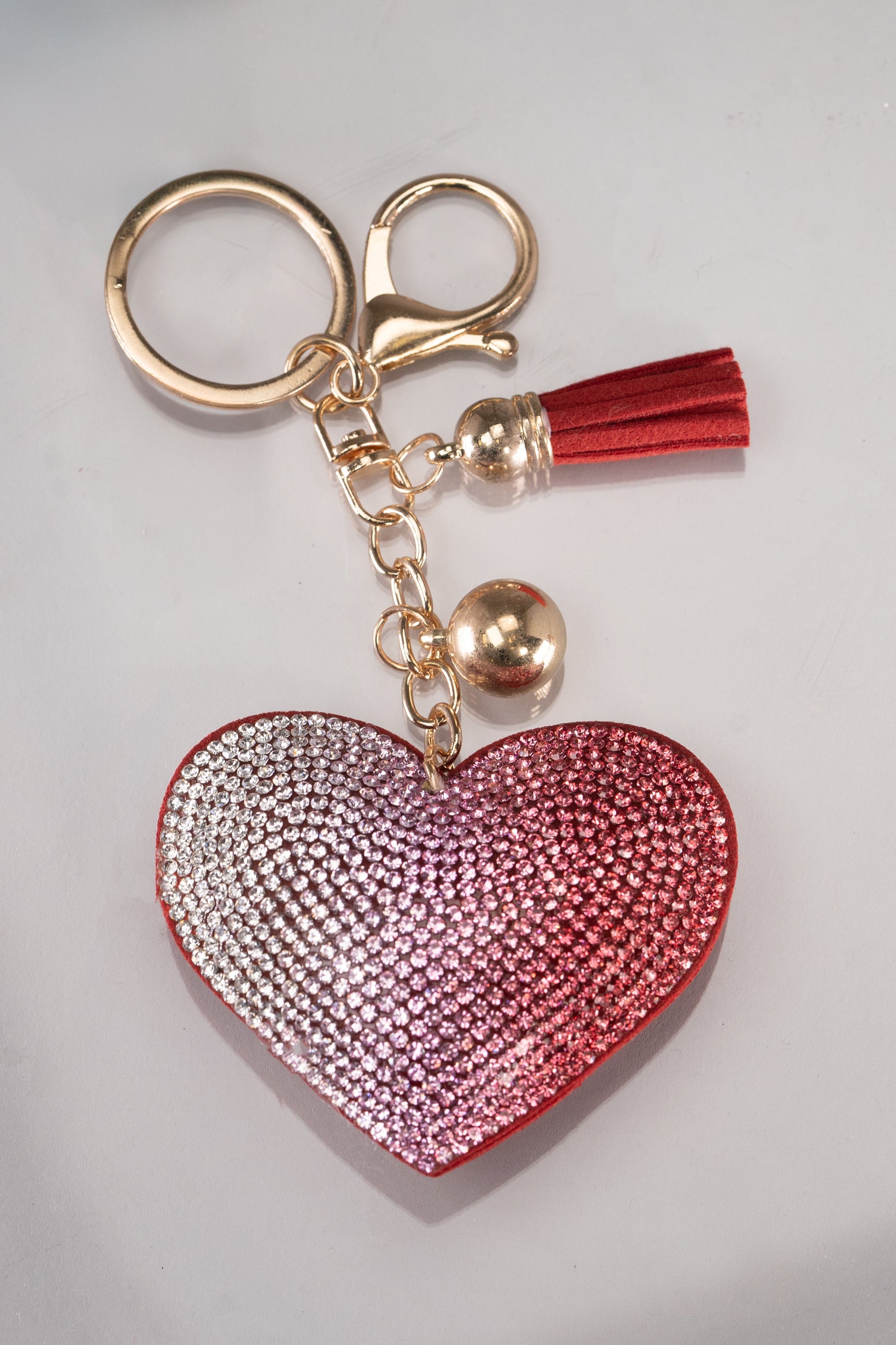 A front view of a red puffy heart keychain with silver, pink and red rhinestone embellishment in an ombre design. 