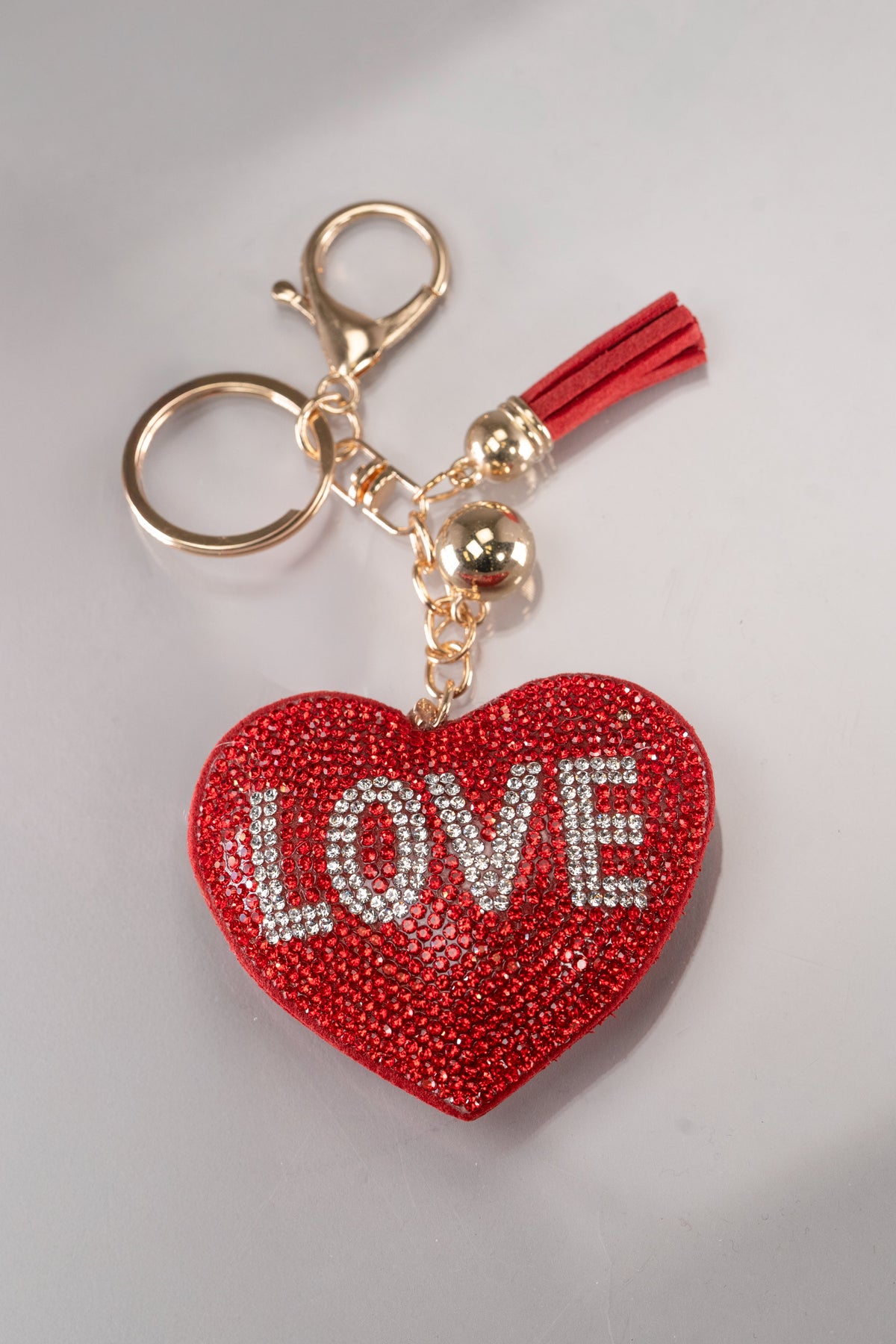 A front view of a red rhinestone puffy heart keychain with &#39;Love&#39; spelled out in silver rhinestones and gold hardware.