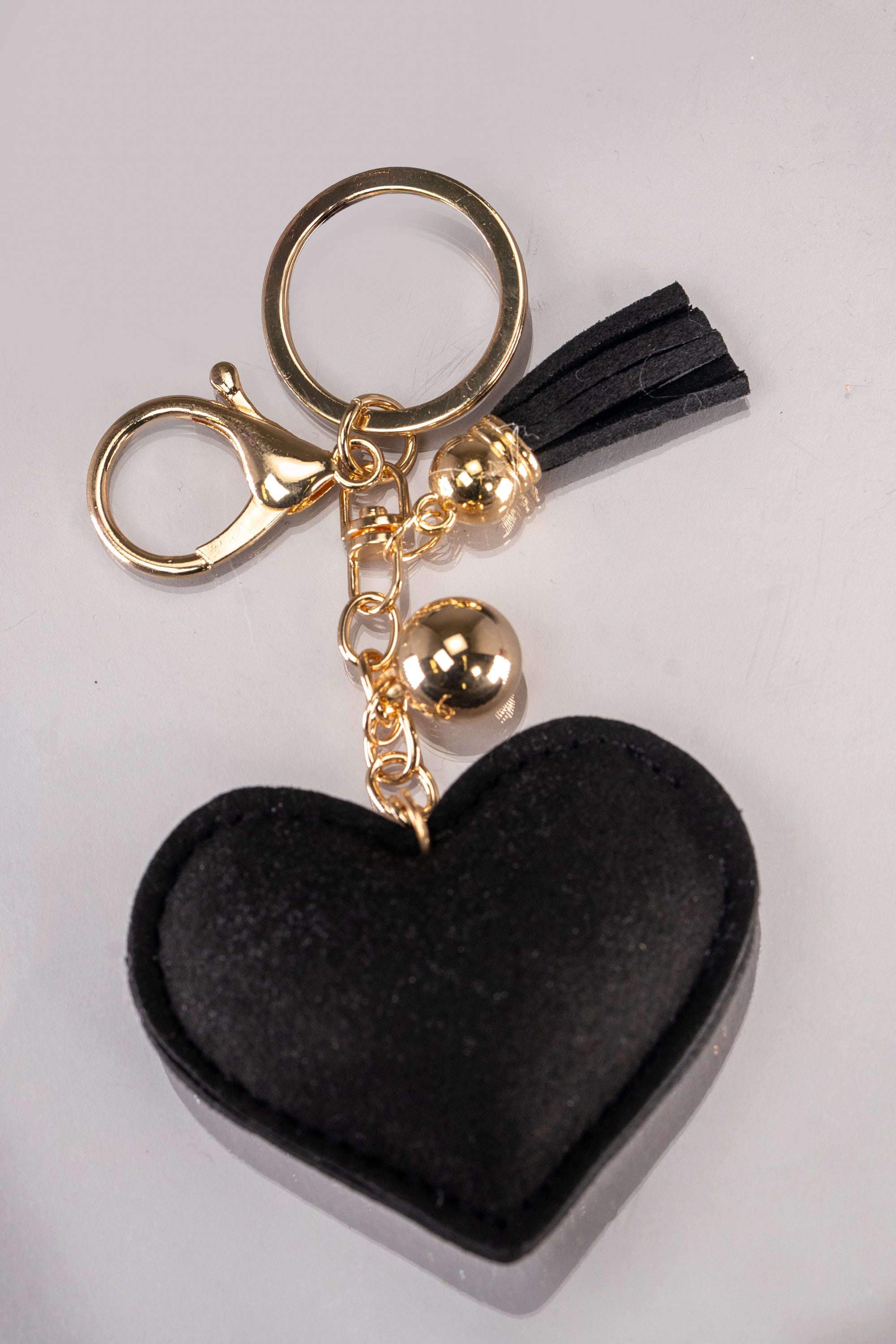 A front view of a black and silver puffy heart keychain with rhinestone embellishment and gold hardware.