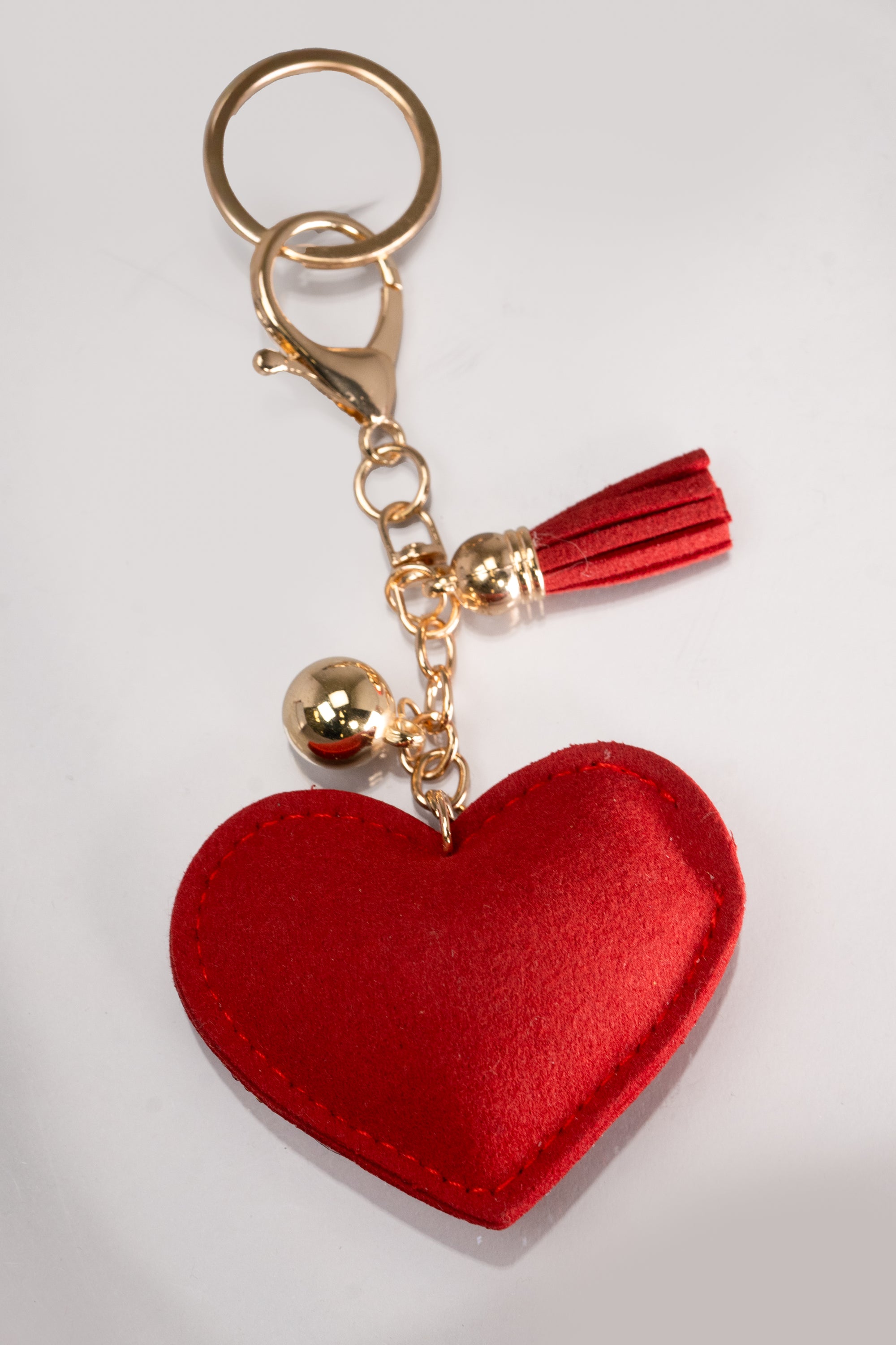 A front view of a red puffy heart keychain embellished with red and AB rhinestones, and has gold hardware.