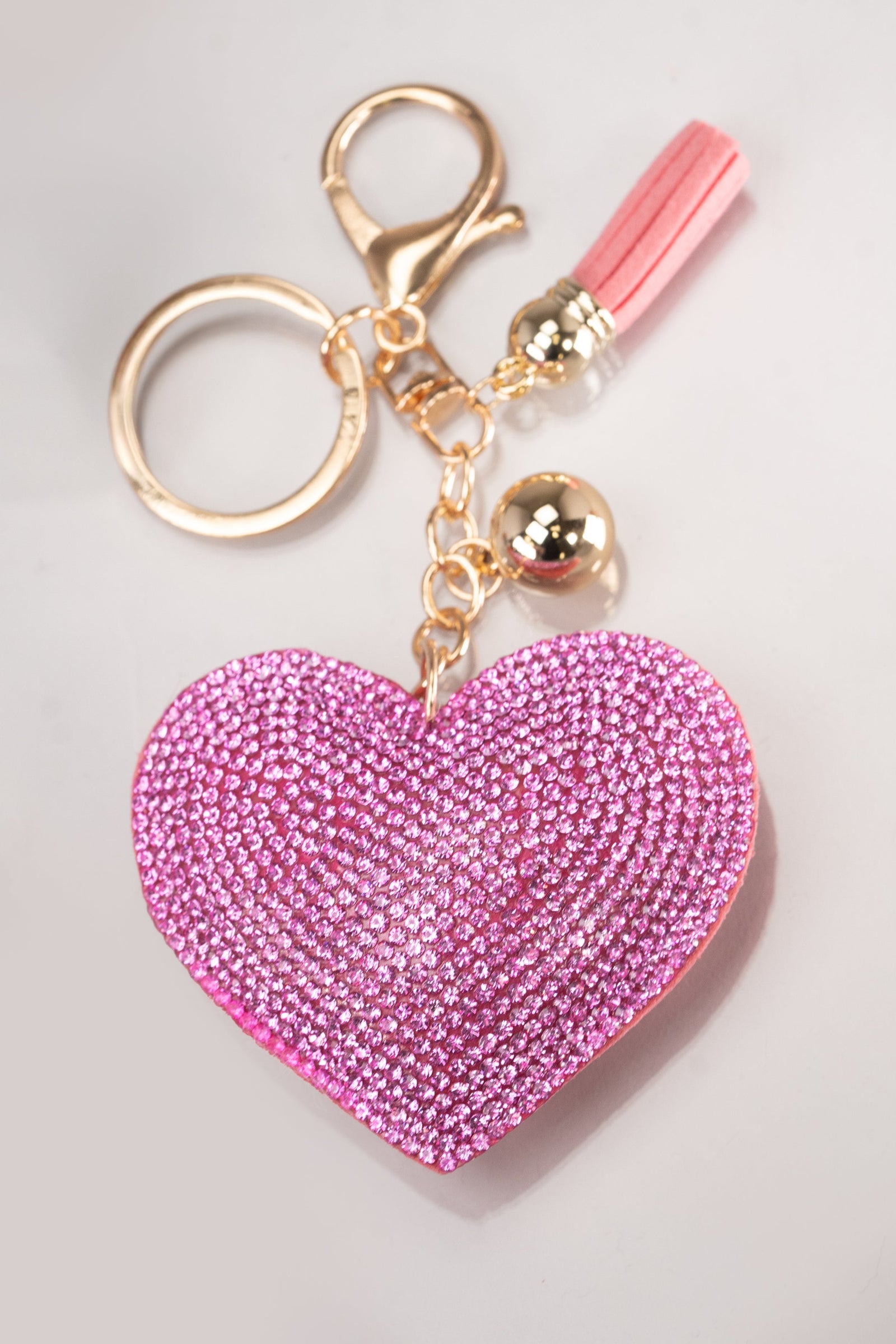 A front view of a pink puffy rhinestone embellished heart keychain with gold hardware.