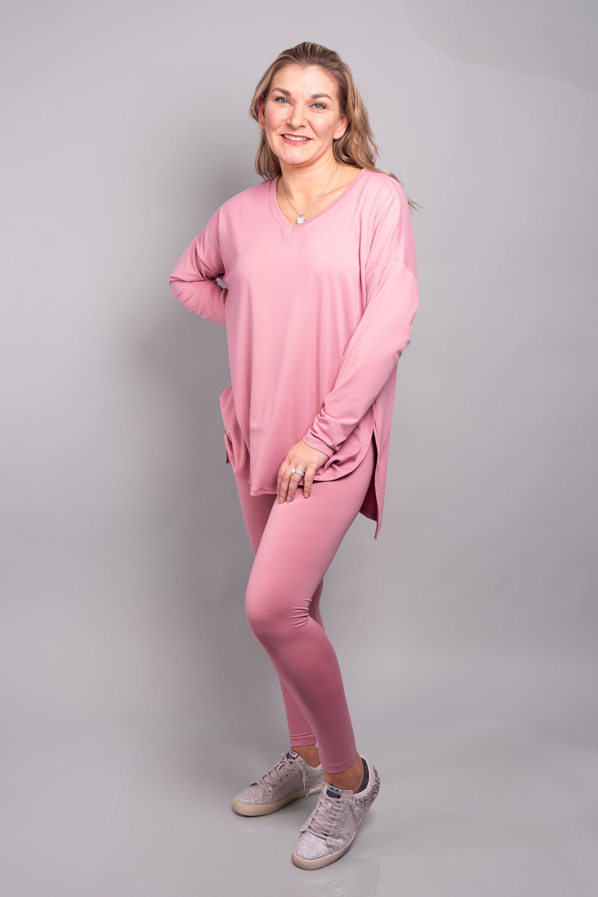 A close-up, front-facing view of our model, Stephanie, wearing our brushed v-neck long sleeved top and leggings set in light rose. 